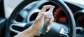 Man hand spraying alcohol sanitizer on steering wheel in his car, against Novel coronavirus or Corona Virus Disease Covid-19. Royalty Free Stock Photo