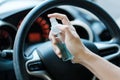 Man hand spraying alcohol sanitizer on steering wheel in his car, against Novel coronavirus or Corona Virus Disease Covid-19. Royalty Free Stock Photo