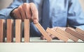 Man hand stopping a falling domino effect of risk. Royalty Free Stock Photo