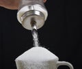 Man hand with sugar bowl pouring a crazy lot in full coffee cup in addiction concept