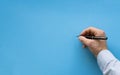 Man hand about to write on blank blue background. Male hand writing on a blank surface with black pen. Close-up hand Royalty Free Stock Photo