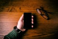 Man hand touch on a screen of mobile phone on a wooden table. Business situation.