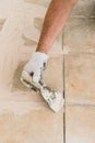 Man hand with trowel plastering a tiles, laying tiles.Construction concept. Selective focus Royalty Free Stock Photo