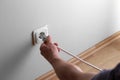 Man hand tyr to plugging electric plug a in a socket on the wall but wire is too short