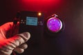 Man hand use dosimeter of radioactive radiation next to an old pocket watch with dangerous fluorescent paint. Violet light and