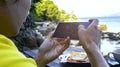 Close up of Man hand using or looking at his smartphone and having lunch in the restaurant near a sand beach beackground