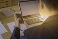 Man hand using mobile phone with laptop on wood table with sheet Royalty Free Stock Photo