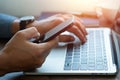 Man hand using mobile phone and typing keyboard of laptop computer on office desk. Royalty Free Stock Photo