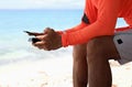 Man hand which texting on smart phone on the beach