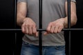 A man in handcuffs in a cell behind bars. Concept: a prisoner in a courtroom, a court sentence to a convicted person, a prison ter Royalty Free Stock Photo