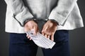 Man in handcuffs holding bribe money on background, closeup Royalty Free Stock Photo