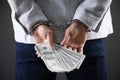 Man in handcuffs holding bribe money on background, closeup Royalty Free Stock Photo