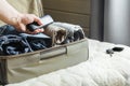 A man handles things. Open suitcase with clothes on the bed. View to the bedroom.