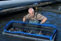 Man handling fishes inside fishing net at fishfarm