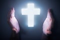 Man hands around shining light from glowing crucifix. Religion concept. Royalty Free Stock Photo