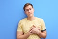 young handsome man wearing casual t-shirt standing over isolated blue background smiling with hands on chest Royalty Free Stock Photo