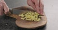 Man hands chopping fresh ginger root with knife on olive wood board