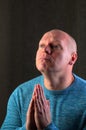 Man with hands clasped in prayer, looking upwards with a contemplative expression Royalty Free Stock Photo