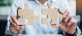 Man hands connecting couple puzzle over table, businessman holding wood jigsaw inside office. Business solutions, mission, target Royalty Free Stock Photo