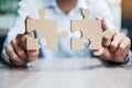 Man hands connecting couple puzzle over table, businessman holding wood jigsaw inside office. Business solutions, mission, target Royalty Free Stock Photo