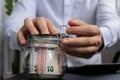 Man hands counting expenses banknotes of euro cash from glass jar in the piggy bank on calculator. Close up of hands