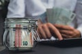 Man hands counting expenses banknotes of euro cash from glass jar in the piggy bank on calculator. Close up of hands