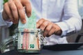 Man hands counting expenses banknotes of euro cash from glass jar in the piggy bank on calculator. Close up of hands