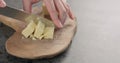 Man hands cut cheddar cheese in cubes on olive wood board Royalty Free Stock Photo