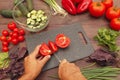 Man hands cut fresh tomato for salad on wooden table