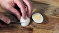 Man hands Cutting Boiled Egg on Wooden Board With Knife. Royalty Free Stock Photo