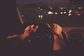 Man hands driver on steering wheel of a modern car with Car dashboard and night city background