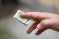 Man hands giving money like a bribe or tips. Holding US dollars banknotes on a blurred background, US currency Royalty Free Stock Photo