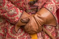 Man hands are gloved and an ornate vintage robe with retro weapons behind an old belt. Male hands in antique clothes with a cane