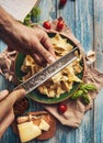 Man hands with grater for cheese over the plate with fresh cooking pasta