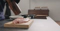 Man hands grind black pepper on chicken fillet on oak board