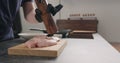 Man hands grind black pepper on chicken fillet on oak board