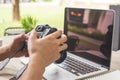 Man hands hand holding camera and using laptop computer in coffee shop. Royalty Free Stock Photo