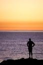 Man with Hands on hips standing on rocks overlooking ocean