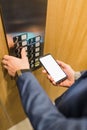 Man hands holding blank screen mobile phone while using elevator control panel Royalty Free Stock Photo