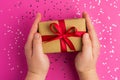 Man hands holding Brown gift boxes with red ribbons. Pink background with multicolored confetti. Flat lay style. Gift for Royalty Free Stock Photo