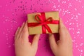Man hands holding Brown gift boxes with red ribbons. Pink background with multicolored confetti. Flat lay style. Gift for Royalty Free Stock Photo