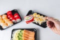 Man hands holding california roll with chopsticks. Lunch boxes, sushi set. Assorted rolls philadelphia, sashimi on light Royalty Free Stock Photo