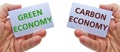 Man hands holding cardstocks with the words green economy and carbon economy