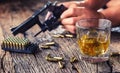 Man hands holding gun and alcohol glass on the table