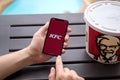 Man hands holding iPhone X with app Kentucky Fried Chicken