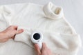 Man hands holding a lint remover from a white acrylic or wool sweater