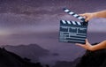 Man hands holding movie clapper on Milky Way , Stars and mountains. Shown slate board. use the colors white and black. Realistic m