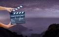 Man hands holding movie clapper on Milky Way , Stars and mountains. Shown slate board. use the colors white and black. Realistic m
