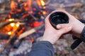 Man hands holding cup near the fire