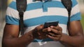 Man hands holding smart phone in urban city. Unrecognizable man using mobile phone outdoors guy wearing t-shirt typing